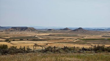 Navarre, İspanya 'daki yarı çöl Bardenas Reales' in panoramik manzarası. Geniş düzlükler engebeli tepeler ve kayalıklarla kesişiyor. Bitki örtüsü kıttır ve ağırlıklı olarak düşük çalı ve otlardan oluşur.. 