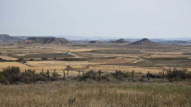 İspanya 'nın Navarre kentindeki Bardenas Reales' in yarı çöl bölgesini kapsayan geniş bir manzara. Arazi kurak yüzeyler, seyrek bitki örtüsü ve aşınmış tepelerin farklı oluşumlarıyla karakterize edilir. 