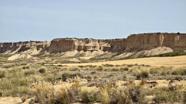 Navarre, İspanya 'daki yarı çöl Bardenas Reales' in panoramik manzarası. Nadir bitki örtüsü olan çorak bir arazi. Arkaplanda engebeli kayalıklar ve kaya oluşumları hakim.