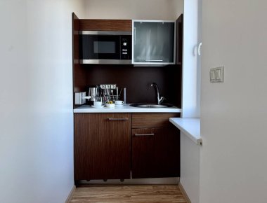 Bir dairede küçük bir mutfak yapma fikri. Gümüş saplı koyu ahşap dolaplar, kazayağı musluğu olan küçük bir lavabo ve dahili mikrodalga fırın içeren kompakt mutfak.. 