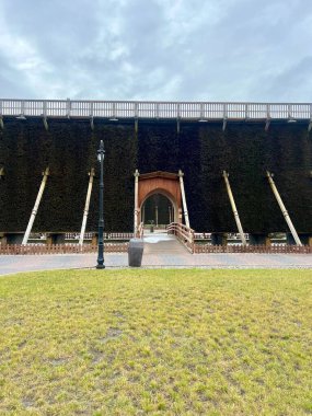 Polonya, Inowroclaw 'daki tuz mezuniyet kulesi. Açılı kirişlerle desteklenen koyu dallarla kaplı yüksek bir duvar içeren büyük ahşap bir yapı. Merkezi ahşap kemer yolu bir yola açılıyor. 