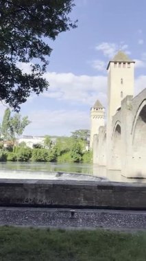 Fransa 'nın Cahors kentindeki ünlü ortaçağ Valentre köprüsünün panoramik manzarası. Üç kulesi olan ortaçağ taş köprüsü yemyeşil ve yuvarlanan tepelerle çevrili sakin bir nehir boyunca uzanır. Fransa şarap rotası. 