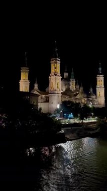İspanya, Zaragoza 'nın gece panoramik manzarası. İspanya 'nın Zaragoza kentindeki Barok tarzı önemli bir katedral olan Our Lady of the Pillar Bazilikası, Ebro Nehri kıyısında görkemli bir şekilde duruyor.. 