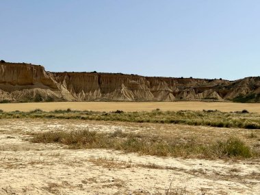 Navarre, İspanya 'daki yarı çöl Bardenas Reales' in panoramik manzarası. Arazi kurak, kayalık ve seyrek bitki örtüsü var. Katmanlı katmanlı aşınmış tepeler 