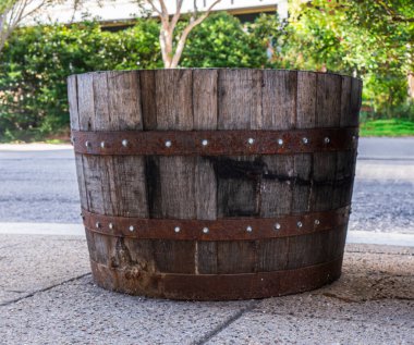 Street planter made from used bourbon barrel showing weathered oak staves and rusted banding. clipart