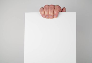 Beyaz erkek, gri arka planda beyaz kart tutuyor.