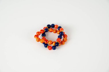 Beyaz arkaplanda mavi ve turuncu boncuklardan bir bilezik.