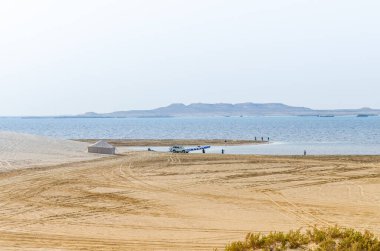 Katar 'daki Al-Adaid Çölü' nün arka planında kireçtaşı tepeleri olan kum tepeleri dereye iniyor.