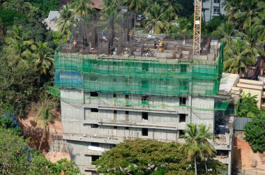 Adamları ve makineleri olan yüksek katlı bir inşaat alanı.