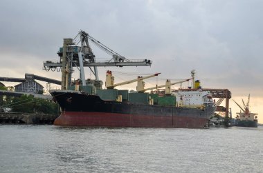 Bulutlu bir muson akşamında limanda bir kargo gemisi.