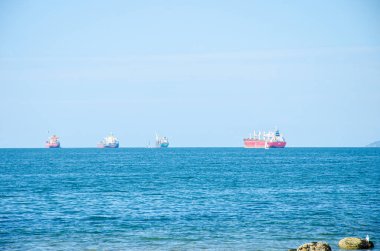 Gemiler arka planda dağlarla bir limana yaklaşıyor.