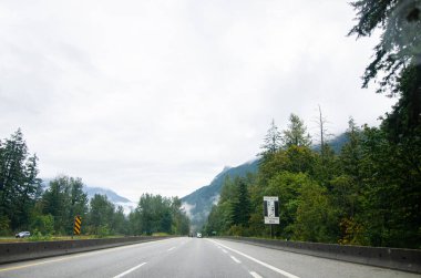 Umut Kanadası, BC otoyolu. Arka planda bulutlarla kaplı dağlar var.