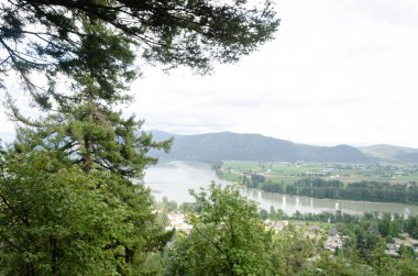 View of the Mission town with Fraser River, lush green valley and the mountains in the background - Fraser Valley, British Columbia, Canada clipart