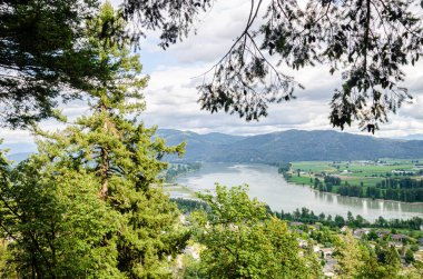 View of the Mission town with Fraser River, lush green valley and the mountains in the background - Fraser Valley, British Columbia, Canada clipart