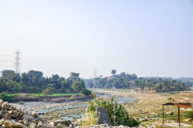 Neredeyse hiç su olmayan kurumuş kayalık nehir yatağı. Nehir kıyısında bir krematoryum yapısı.