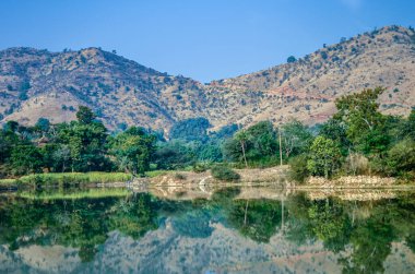 Udaipur 'dan Kumbalgarh Kalesi, Rajasthan, Hindistan' a giden kayalık arazide kıvrılan tatlı su nehirinin manzarası.