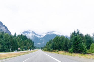 Umut Kanadası, BC otoyolu. Arka planda bulutlarla kaplı dağlar var.