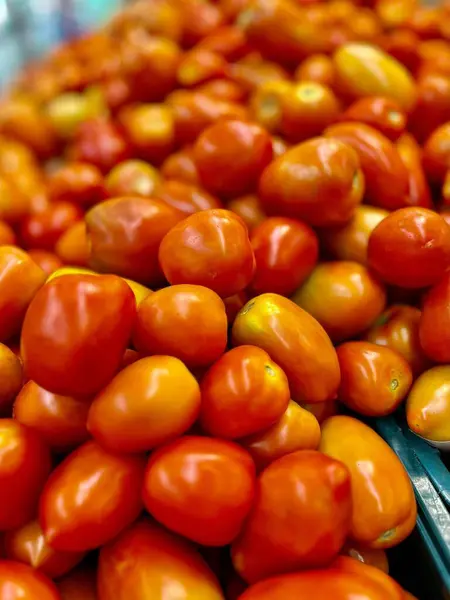 Canlı, taze domatesler üst üste yığılmış. Parlak kırmızı renklerini ve etli dokularını gösteriyorlar. Pişirmek ve salata eklemek için mükemmel..