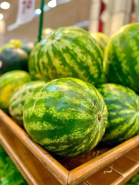 Market rafında taze ve sulu karpuzlar. Yeşil, çizgili kabuklar ışıkta parlıyor, tazelik ve doğa hissi uyandırıyor..