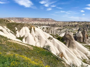 Büyüleyici ve eşsiz doğa ve kaya oluşumunun hava ve panoramik görüntüsü, Kapadokya 'nın peri bacaları, Goreme, Türkiye' nin güzel bir bahar günü mavi gökyüzü, sarı kır çiçeklerinin açtığı
