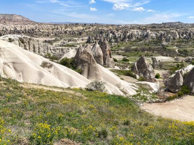 Büyüleyici ve eşsiz doğa ve kaya oluşumunun hava ve panoramik görüntüsü, Kapadokya 'nın peri bacaları, Goreme, Türkiye' nin güzel bir bahar günü mavi gökyüzü, sarı kır çiçeklerinin açtığı