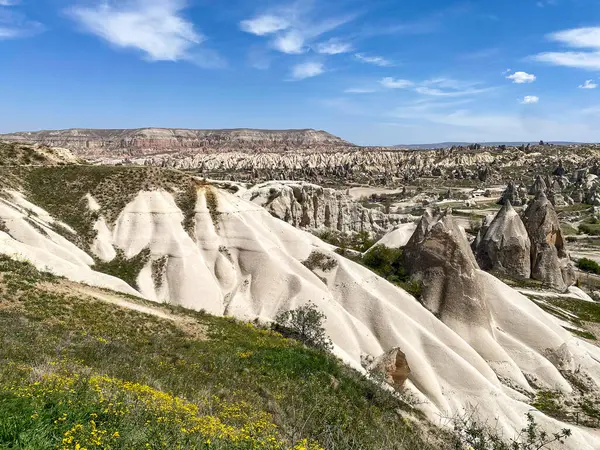 Büyüleyici ve eşsiz doğa ve kaya oluşumunun hava ve panoramik görüntüsü, Kapadokya 'nın peri bacaları, Goreme, Türkiye' nin güzel bir bahar günü mavi gökyüzü, sarı kır çiçeklerinin açtığı