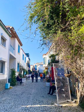 Alacati 'nin küçük, sevimli bir kasabası, kaldırımtaşı sokak aralığı, canlı ve modaya uygun kafeler, restoranlar ve güzel renkli dekorasyonlarla dolu. 