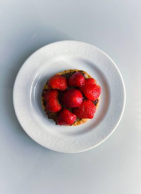 Fındık kremalı waffle, çikolata ve küçük beyaz bir porselen tabakta servis edilen güzel kırmızı çilekler. 