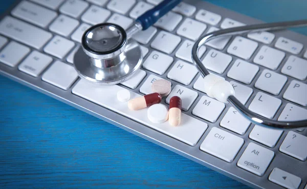 Pills and stethoscope on the computer keyboard.