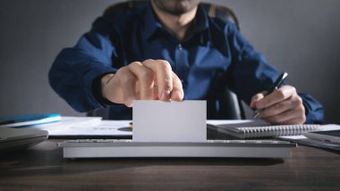 Ofiste oturan bir iş adamı beyaz, boş bir kartvizit gösteriyor..