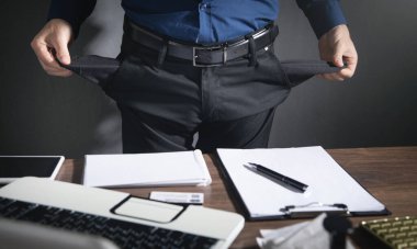 İş adamı iş yerinin yanında dururken boş cepler gösteriyor.