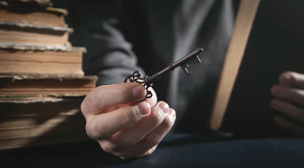 Man holding old key with a book.