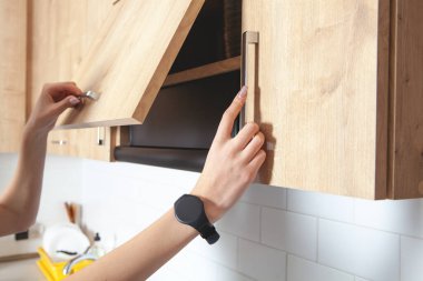 Beyaz kadın mutfak kapısının mobilyalarını açıyor..