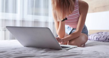 Evde çalışıyorum. Kız laptopuyla yatakta çalışıyor.