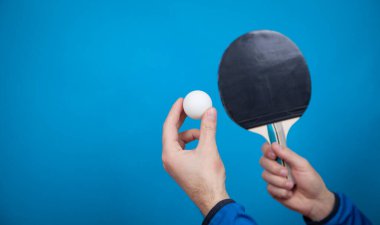 Tenis raketi ve beyaz plastik top tutan adam..