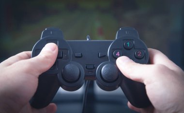 Eller joystick kullanıyor. Bilgisayar ekranında video oyunu oynanıyor