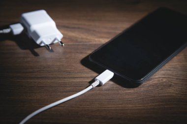 Akıllı telefon ahşap masada şarj oluyor..