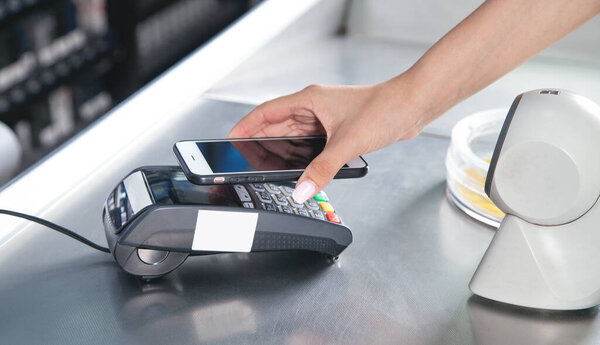 Customer paying for purchases contactless with smartphone.