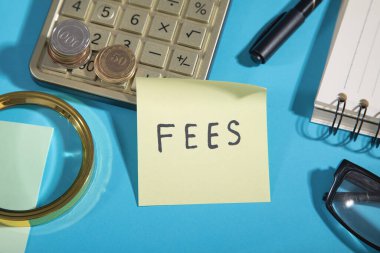 Hesap makinesi, bozuk para ve işaretleyici ile metin beyanları yapışkan bir notta.