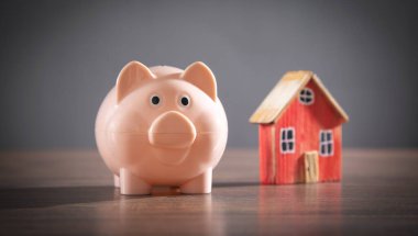 Domuz kumbarası ve ev modeli masada..