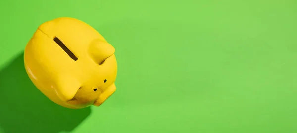 Yellow piggy bank on the green paper background.