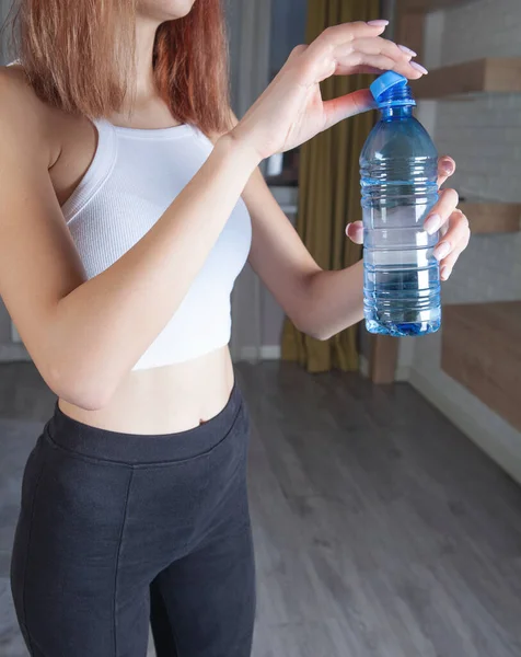 Woman holding bottle of water. Exercise at home