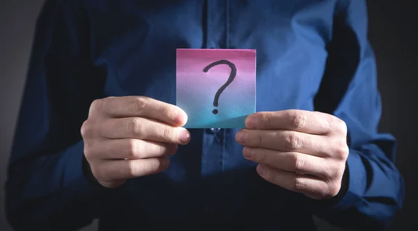 Man showing question mark on sticky note.