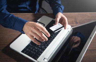 Dizüstü bilgisayar kullanan ve kredi kartı tutan bir iş adamı..