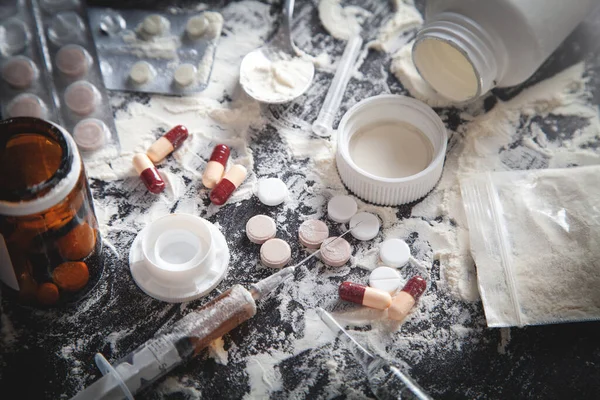 Eroin tozu, haplar ve siyah arka planda şırınga..