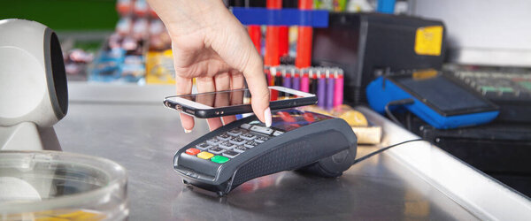 Customer paying for purchases contactless with smartphone.