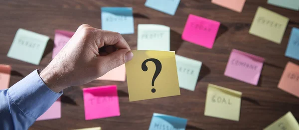 Man showing question mark on sticky note.