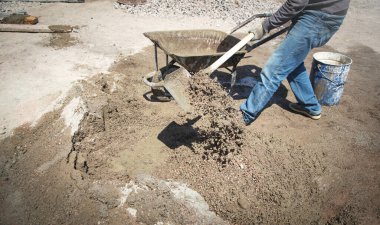 İşçiler inşaat alanında kürekle beton hazırlıyorlar..