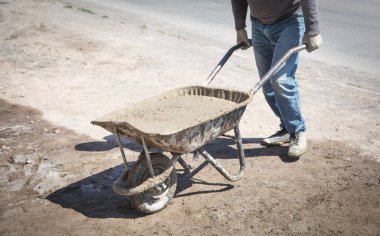 İnşaat işçisi çimento el arabası itiyor..