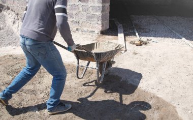 İnşaat işçisi çimento el arabası itiyor..